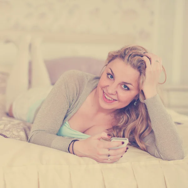 Yatak telefon ederek üzerinde sarışın kadın — Stok fotoğraf