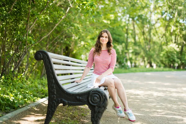 Modelo senta-se em um banco de parque — Fotografia de Stock