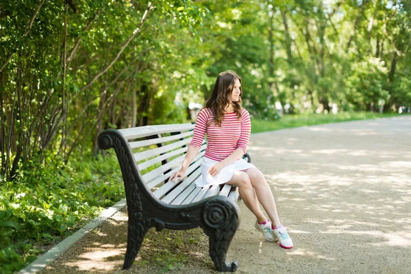 Model sits on a park bench — Stock Photo, Image