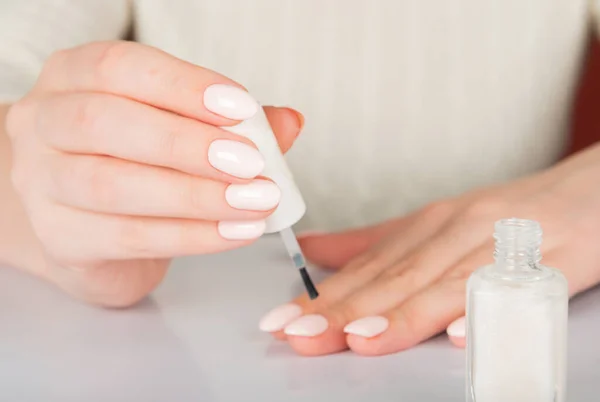 woman's hands with white nail varnish bottles. Nails car