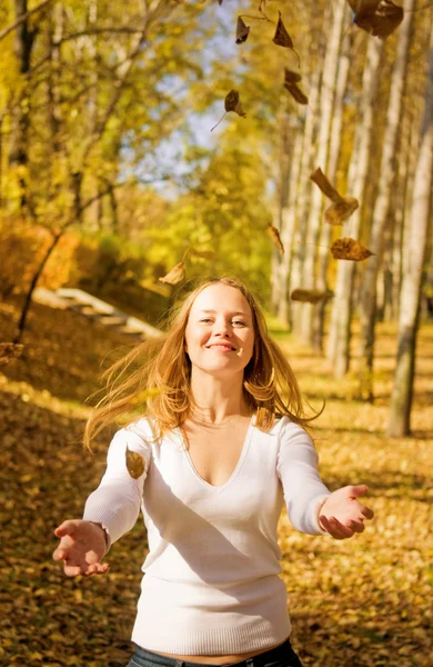 Flicka kastar hösten lämnar — Stockfoto