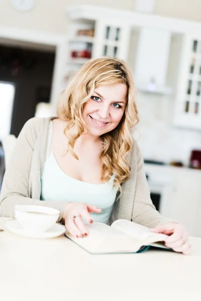 Beautiful woman reads an interesting book and drinks coffee — Stock Photo, Image