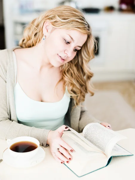 Mooie vrouw een interessant boek leest en drinkt koffie — Stockfoto