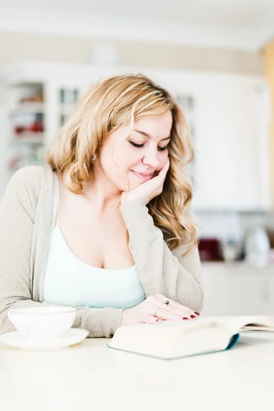 Hermosa mujer lee un libro interesante y bebe café —  Fotos de Stock