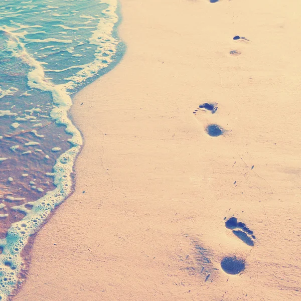 Footprints on sand with foam — Stock Photo, Image