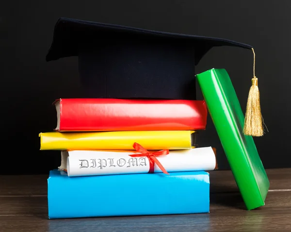 A mortarboard and graduation scroll on books — Stock Photo, Image