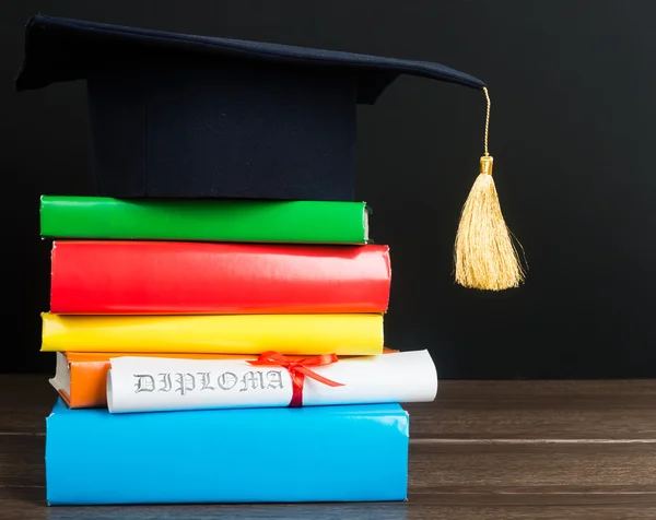 A mortarboard and graduation scroll on books — Stock Photo, Image