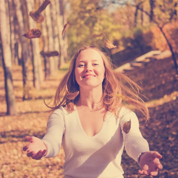 Glückliches Mädchen wirft Herbstblätter — Stockfoto