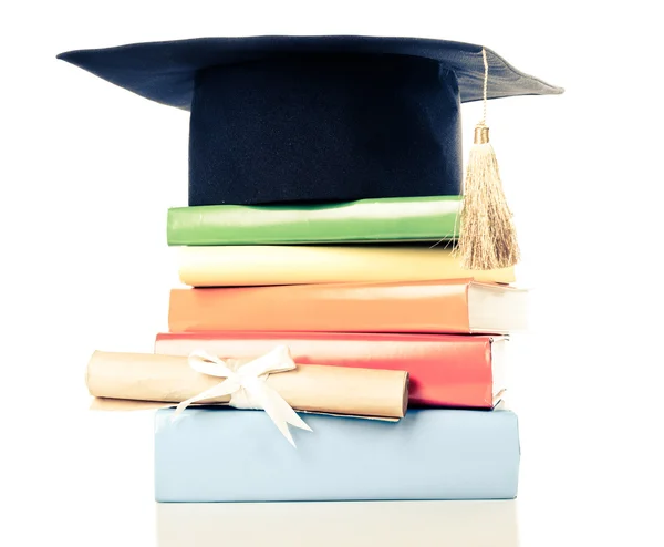 A mortarboard and graduation scroll on books — Stock Photo, Image