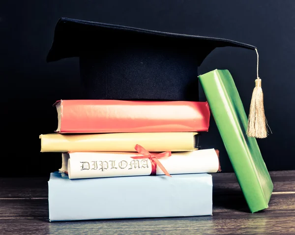 A mortarboard and graduation scroll on books — Stock Photo, Image