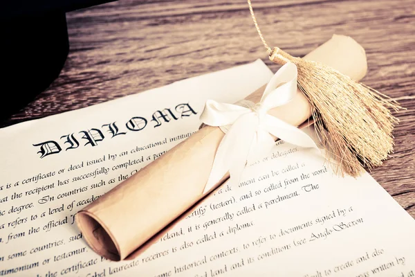 Un diploma y un sombrero de graduado — Foto de Stock