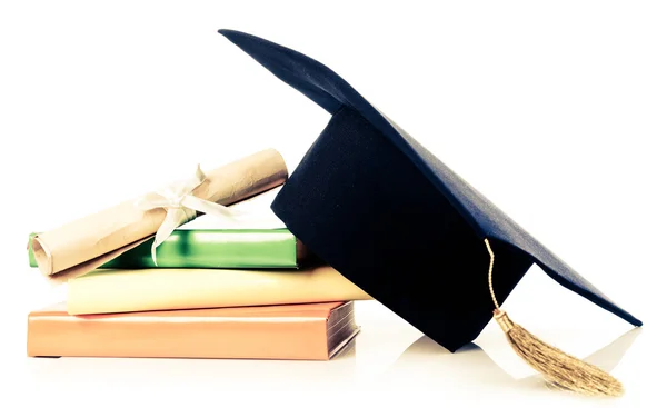A mortarboard and graduation scroll on books — Stock Photo, Image
