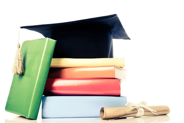 A mortarboard and graduation scroll on books — Stock Photo, Image