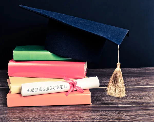 Un mortarboard e una pergamena di consegna delle lauree sui libri — Foto Stock