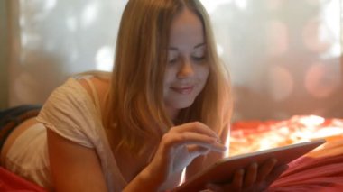 woman using tablet lying on her bed