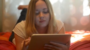 woman using tablet lying on her bed