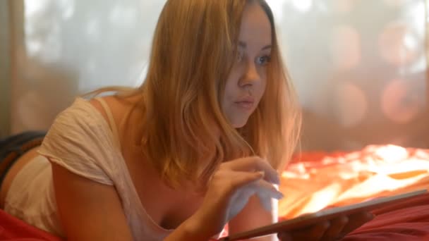 Woman using tablet lying on her bed — Αρχείο Βίντεο