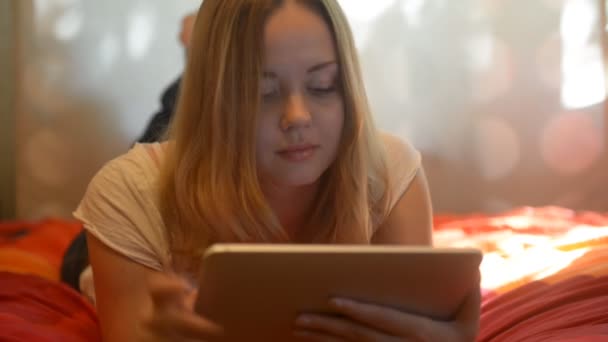 Woman using tablet lying on her bed — Stock video