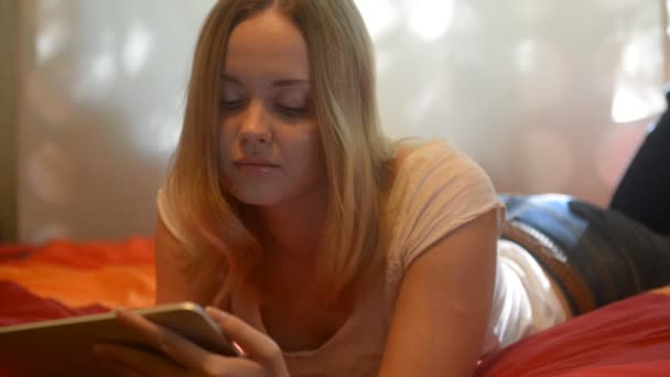 Mujer usando la tableta acostada en su cama — Vídeo de stock