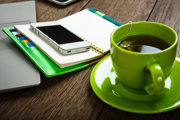 Office desk with laptop and cup of tea — Stock Photo, Image