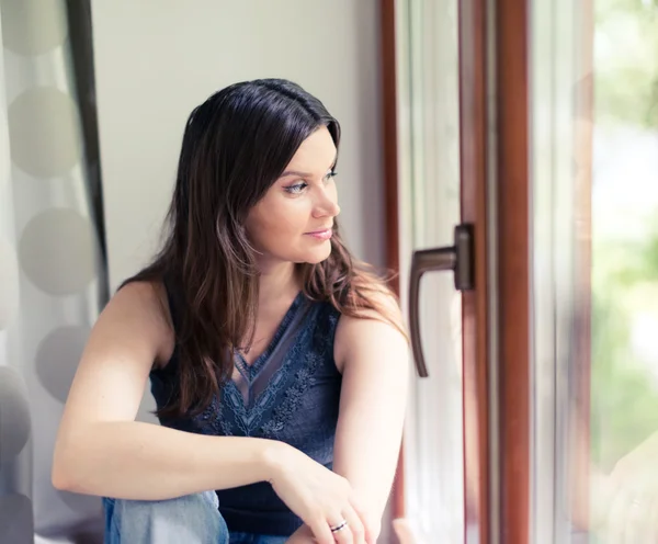 Atrakcyjna kobieta patrząc w okno — Zdjęcie stockowe
