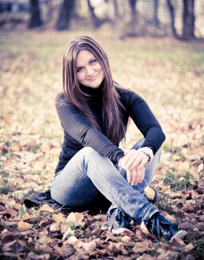 sonbahar Park yapraklarda kadın oturur