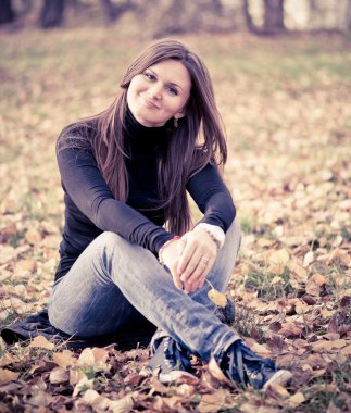 genç kadın parkta yapraklarda oturur