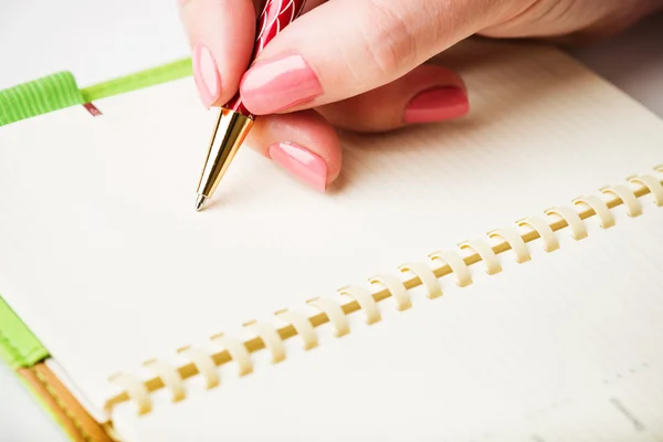 Weibliche Hand mit Stift schreibt auf Notizbuch — Stockfoto