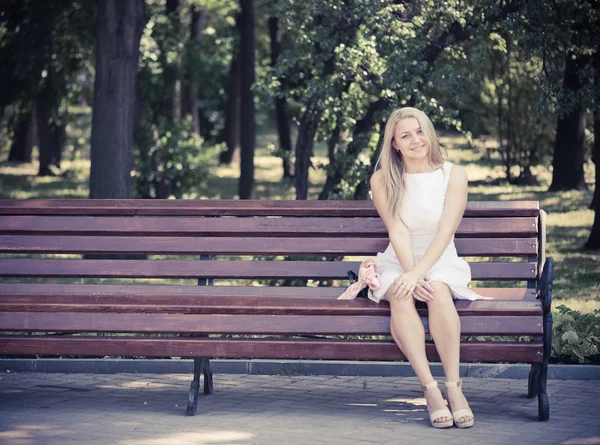 Žena sedí na lavičce v parku — Stock fotografie