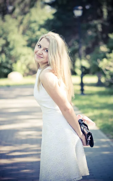 Blonde vrouw in een witte jurk buitenshuis — Stockfoto