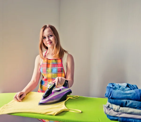 Kvinnan stryka kläder i rum — Stockfoto