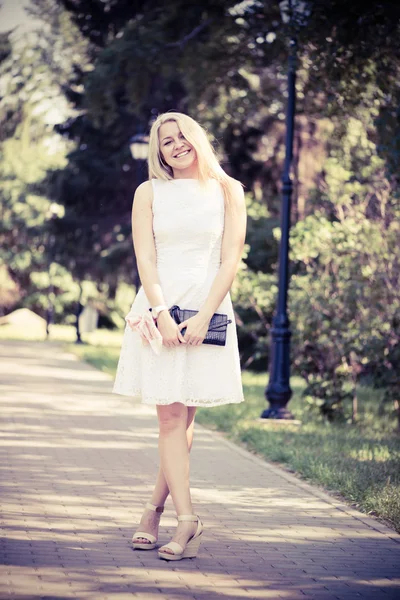 Blonde vrouw in een witte jurk buitenshuis — Stockfoto