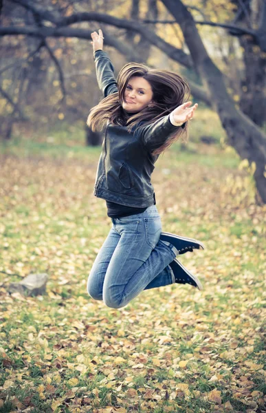 Ragazza in giacca nera salta nel parco — Foto Stock