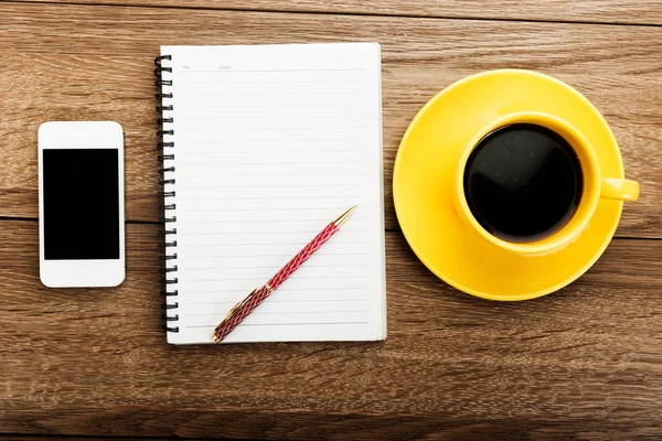 Lugar de trabajo con teléfono, notebook, pluma y taza —  Fotos de Stock