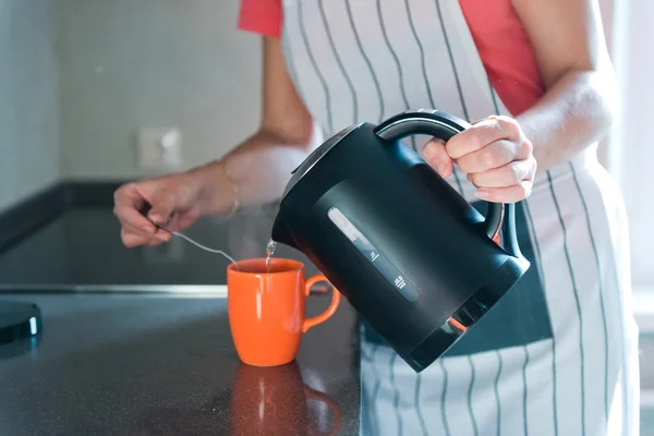 Derramando bebida quente para a caneca — Fotografia de Stock