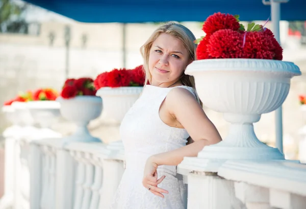 Vrouw in de buurt van rode bloemen in witte vazen — Stockfoto