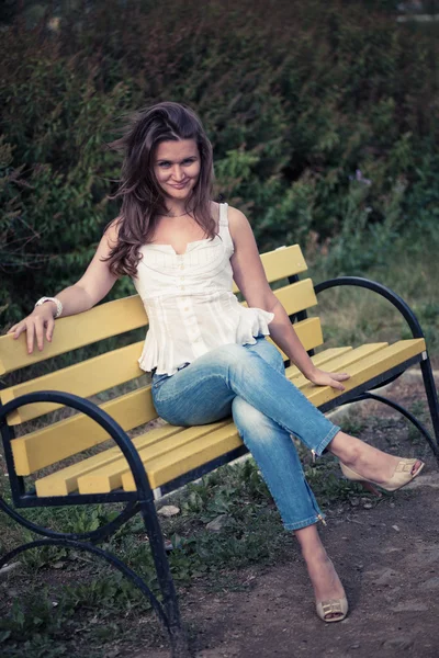 Vrouw aanbrengen op een bankje in het park — Stockfoto