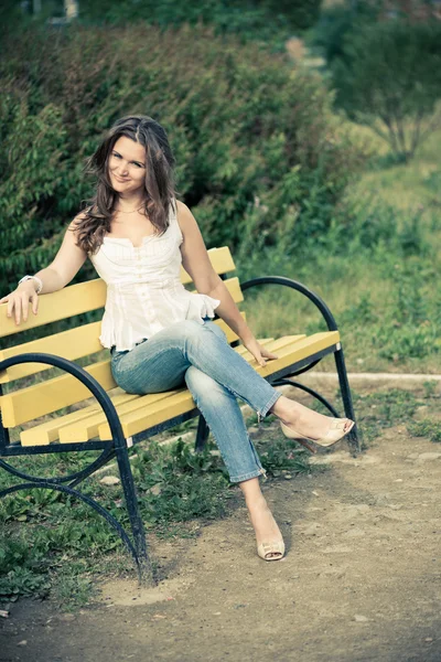 Жінка сидить на лавці в парку — стокове фото