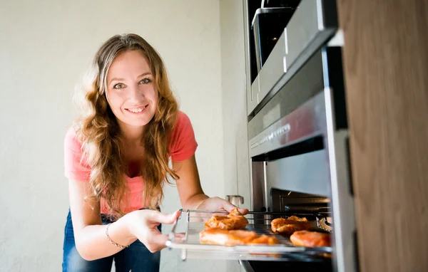 Woman putting meat into oven — Stock Photo, Image