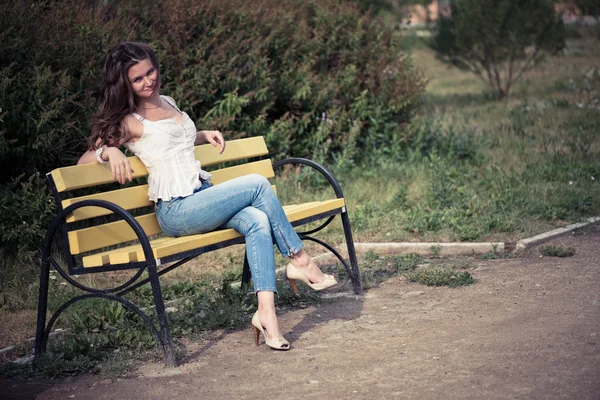 Mulher sentada em um banco no parque — Fotografia de Stock