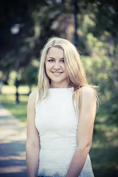 Blonde vrouw in een witte jurk buitenshuis — Stockfoto