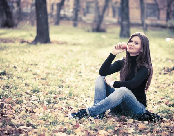 Mujer joven con manzana en el parque de otoño — Foto de Stock