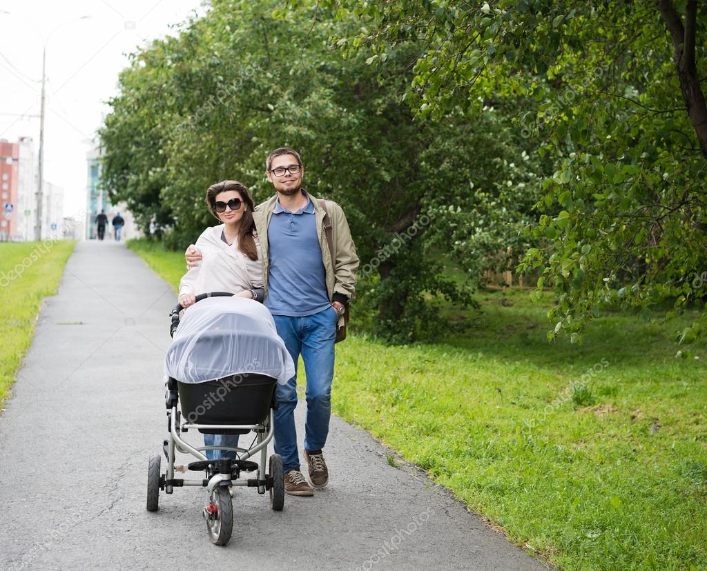 Man and woman walking with baby pram — Stock Photo © valphoto