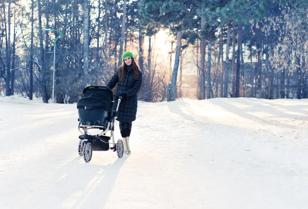 Woman with stroller in winter park — Stock Photo, Image