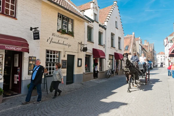 At arabası ve turistler Brugge sokaklarında. — Stok fotoğraf