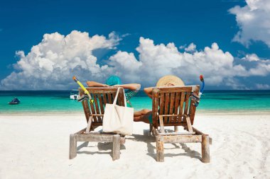 Yeşilli çift Maldivler 'de tropikal bir plajda dinleniyor.