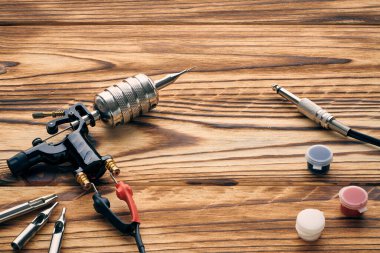 Dövme makinesi, aletler ve malzemeler ahşap arka planda. Dövme stüdyosu.