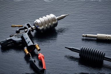 Dövme makinesi, araç gereç ve gereçler siyah tahta üzerine. Dövme stüdyosu.