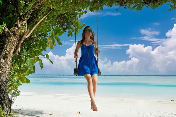 穿着蓝色衣服的女人在热带海滩荡秋千 — 图库照片