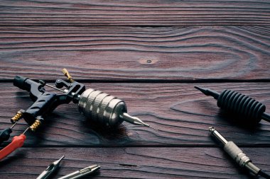 Dövme makinesi, aletler ve malzemeler ahşap arka planda. Dövme stüdyosu.